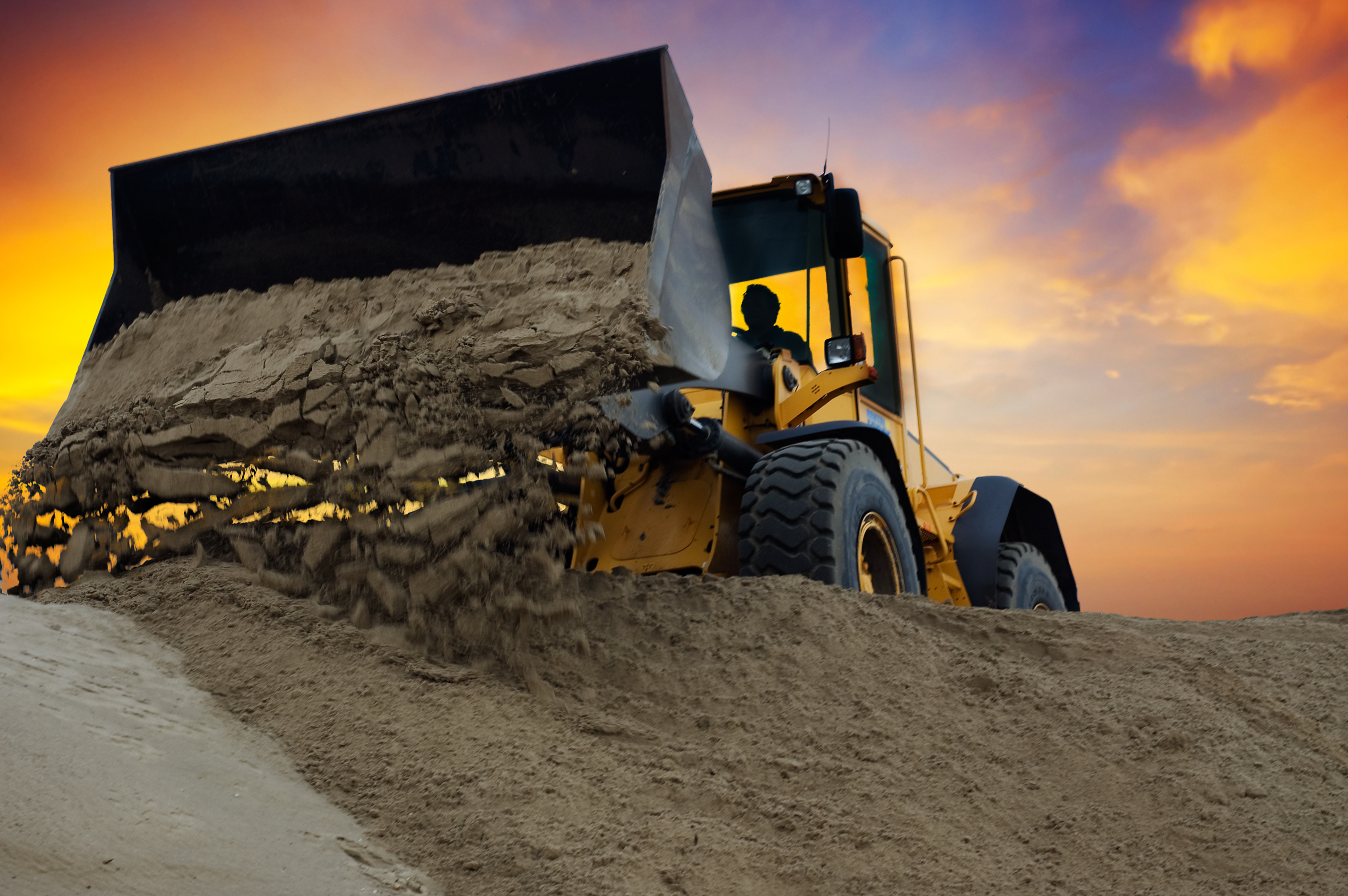 Loader moving dirt at sunset